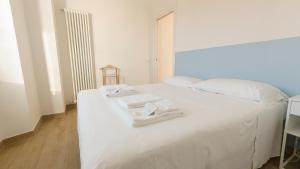 ein weißes Bett mit zwei Handtüchern darüber in der Unterkunft Noliday Riviera Sea View Luxury Apartment in Noli