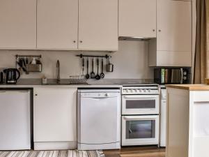 uma cozinha com electrodomésticos brancos e armários brancos em Farthing em Epsom