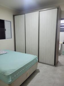 1 dormitorio con 1 cama y puertas correderas de cristal en Bela Mar Mongaguá en Mongaguá