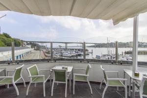 a balcony with tables and chairs and a view of a marina at Hotel Alda Fogar do Mariñeiro in Ribadeo