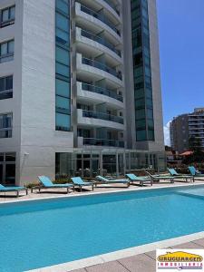 uma piscina com espreguiçadeiras e um edifício em Apartamento Punta del Este,Wind Tower 2 dormitorios em Punta del Este