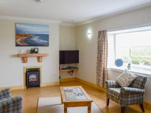 a living room with a fireplace and a tv at Sheaf Dale in Portmahomack