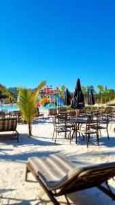 Santíssimo Resort في تيرادينتيس: مجموعة من الكراسي والطاولات على الشاطئ