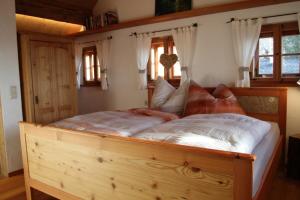 Cama grande de madera en habitación con ventanas en Die Mirnockhütte, en Ferndorf