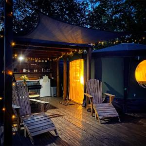 una terraza con 2 sillas y una cocina con luces en Yurt at Le Ranch Camping et Glamping, en Madranges