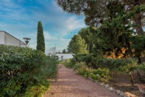 einen Pfad in einem Garten mit Bäumen und Sträuchern in der Unterkunft Maison Ohana 4-6 pers dans résidence Privée près de la Plage in Canet-en-Roussillon