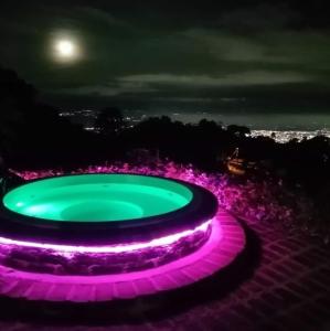 une fontaine violette et verte la nuit avec la lune dans l'établissement Romero Glamping y Cabañas, à Cali