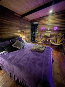 卡利的住宿－Romero Glamping y Cabañas，一间卧室配有一张大紫色床和两把椅子