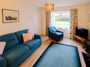 a living room with a blue couch and a chair at Fishers Cottage in Balintore