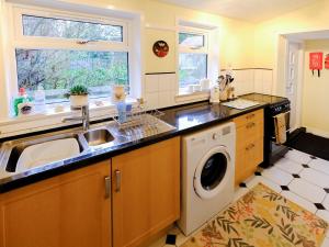 a kitchen with a sink and a washing machine at Fishers Cottage in Balintore