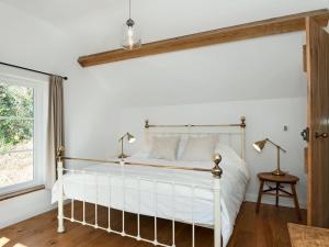 1 dormitorio con cama blanca y ventana en The Mill House, en Aisholt