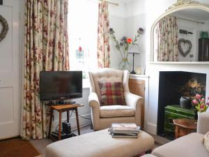 a living room with a chair and a television at The Old Laundry Cottage in Hythe