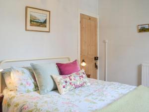 a bed with colorful pillows on top of it at The Old Laundry Cottage in Hythe