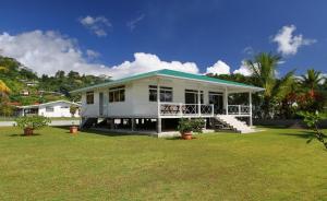 une maison blanche avec un toit vert sur une cour dans l'établissement RAIATEA - Fare Te Hanatua, à Tevaitoa