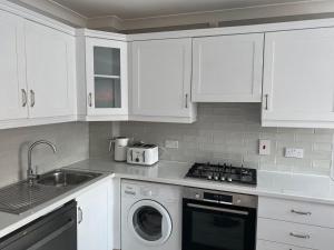 a kitchen with white cabinets and a washing machine at Modern house in Dublin in Dublin