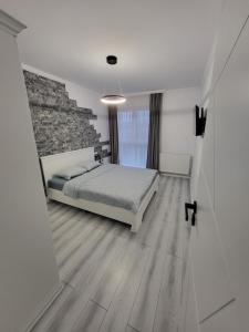 1 dormitorio con cama y pared de piedra en Dacrilo Apartments Cluj-Napoca 12 en Cluj-Napoca