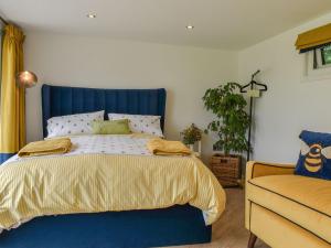 a bed with a blue headboard in a bedroom at Honeypot Lodge in Ashwater
