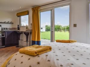 a bedroom with a bed and a kitchen with windows at Honeypot Lodge in Ashwater