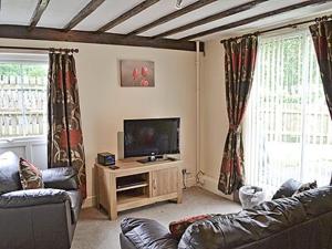 a living room with a couch and a flat screen tv at Cartmel Cottage in Lindale