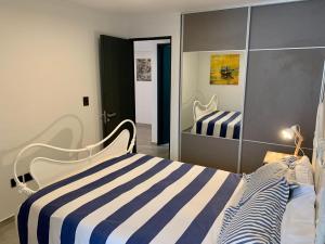 1 dormitorio con cama de rayas y espejo en Depto a Estrenar 1 dormitorio con balcón en Córdoba
