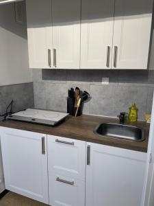 a kitchen counter with white cabinets and a sink at Appartement au Sauze vue montagne in Enchastrayes