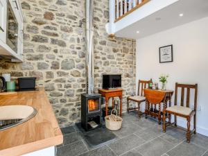 cocina y sala de estar con estufa de leña en The Hayloft - Uk40092, en Bryngwyn