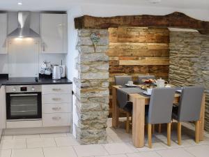 a kitchen with a dining table and a stone wall at Cilwendeg Lodge in Newchapel