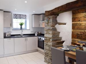 a kitchen with white cabinets and a stone wall at Cilwendeg Lodge in Newchapel