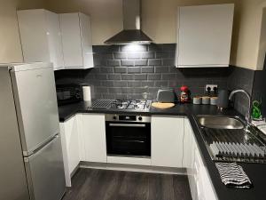a kitchen with white cabinets and a stove top oven at Dads 2 in Balby