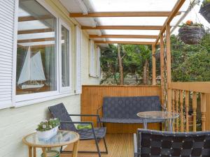 eine Veranda mit zwei Stühlen, einem Tisch und einem Segelboot im Fenster in der Unterkunft Stable Cottage in Carisbrooke