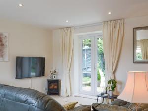 a living room with a couch and a television at Stable Cottage in Carisbrooke