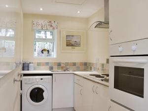 a white kitchen with a washing machine in it at Stable Cottage in Carisbrooke