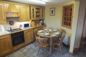 una cucina con tavolo con sedie e forno a microonde di Barnwell Farm Cottages Corn cottage a Greyabbey Altre 21 foto