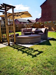 a couch sitting in a yard with an umbrella at Magnolia House in Nantwich