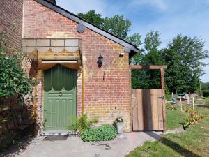 een bakstenen gebouw met een groene deur en een poort bij Le Petit Refuge 