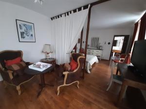 ein Wohnzimmer mit einem Tisch, Stühlen und einem Bett in der Unterkunft La maison de Maria in Saint-Beauzire