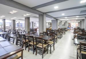 um restaurante com mesas e cadeiras de madeira e janelas em Boulevard Beach Canasvieiras Hotel em Florianópolis