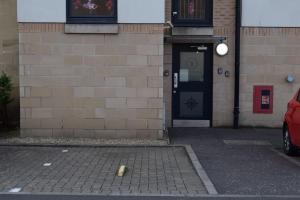 un bâtiment avec une porte et une voiture garée devant lui dans l'établissement THE PAISLEY PENTHOUSE - ABBEY VIEW, à Paisley