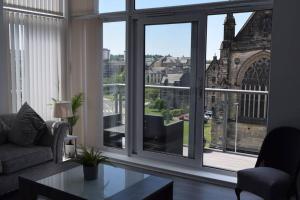 een woonkamer met een raam met uitzicht op een kathedraal bij THE PAISLEY PENTHOUSE - ABBEY VIEW in Paisley