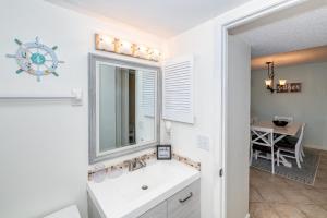 La salle de bains est pourvue d'un lavabo, d'un miroir et d'une table. dans l'établissement Unit 4307 - Ocean Racquet Club, à Saint Augustine Beach