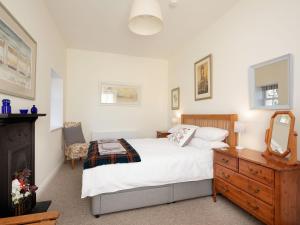 a bedroom with a bed and a dresser and a mirror at Nettlebush Cottage-uk5629 in Drummelzier