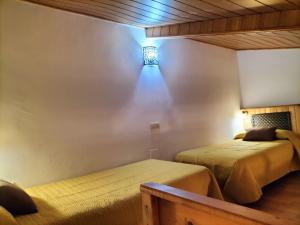 a bedroom with two beds and a light on the wall at Don Camino in Villalcázar de Sirga