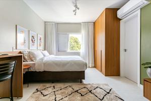 Schlafzimmer mit einem Bett, einem Schreibtisch und einem Fenster in der Unterkunft Predio com apartamentos completos, com piscina e a passos da praia - Agua Marinha in Florianópolis