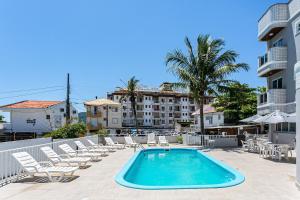 a swimming pool with lounge chairs and a hotel at Prédio com apartamentos completos, com piscina e a passos da praia - Agua Marinha in Florianópolis
