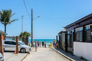 a group of people walking down a sidewalk near the beach at Prédio com apartamentos completos, com piscina e a passos da praia - Agua Marinha in Florianópolis