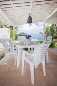 una mesa blanca y sillas en un patio con vistas al océano en La Feliz - Casa de Praia, en Porto de Galinhas