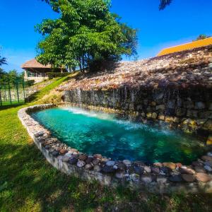 una piscina de agua junto a una pared de piedra en Finca Thakni' Casa de Campo, en Aquismón