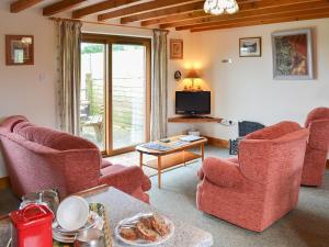 een woonkamer met 2 stoelen en een televisie bij Merlin View in Saint Mawgan