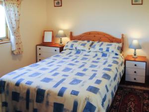 een slaapkamer met een bed met een blauw en wit dekbed bij Merlin View in Saint Mawgan