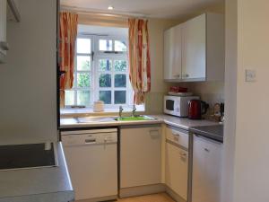 西德伯里的住宿－The Granary，厨房配有白色橱柜、水槽和窗户。